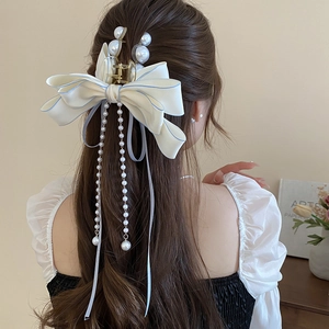Detail of elegant bow hair claw clip with long pearl tassels on a model hair