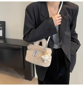Detail of beige fleece crossbody bag with white strap and plush charm on a model