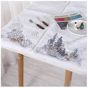 Detail of white plush Christmas table runner featuring embroidered snowflakes and pine trees