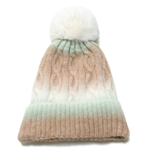 Close-up of tricolor gradient knit beanie with white faux fur pompom and cable texture