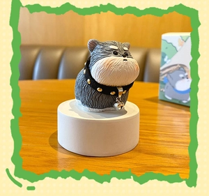 Close-up of cute grey resin dog figurine with black spiked collar and silver bell accessory