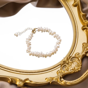 Close-up of Baroque freshwater pearl bracelet with gold clasp on vintage mirror