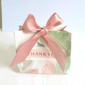 Detail of pink floral gift bag featuring a silk ribbon bow and THANK YOU text design