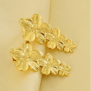 Macro view of triple gold flower earrings with embossed textures on champagne silk