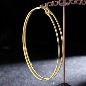 Detailed view of large gold hoop earrings hanging on a vintage jewelry stand