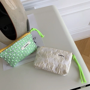 Close-up of small zipper pouch with green geometric pattern and yellow puller detail