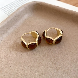 Macro shot of vintage gold-plated C-shape hoop earrings with amber resin beads