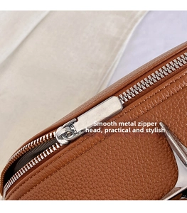 Macro shot of silver metal zipper pull and textured brown lychee leather detail on the bag