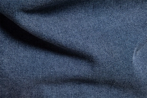 Macro shot of dark blue denim cotton twill fabric showing detailed texture and weave