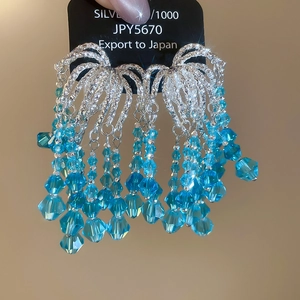 Close-up of luxury beaded tassel earrings with light blue crystals and silver finish