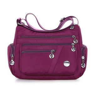 Dettaglio della borsa a tracolla in nylon viola con tasche multiple e finiture argentate
