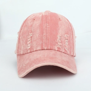Close-up of distressed details and frayed edges on washed pink denim baseball cap