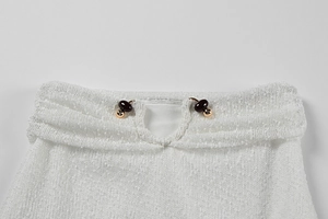 Close-up of white knitted collar with delicate mesh texture and bead fastener detail