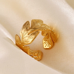 Elegant gold leaf stainless steel open ring with detailed engraving on silk background