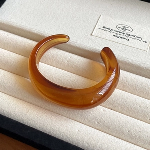 Detailed view of amber resin chunky wave bracelet on beige velvet jewelry display