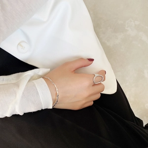 Minimalist irregular open ring and wavy silver bracelet worn with white blazer