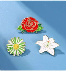 Detailed view of enamel pins featuring red rose, daisy, and white lily on blue background