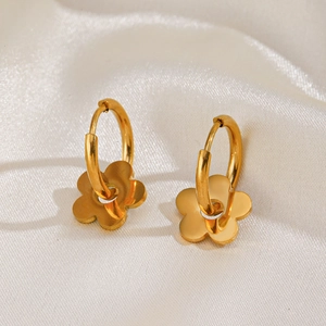 Boucles d'oreilles fleur en acier plaqué or 18K sur un fond luxueux en soie beige