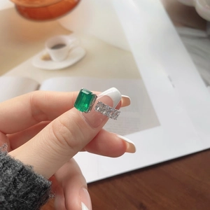 Macro detail of an emerald-cut green stone ring with zircon accents worn during tea time