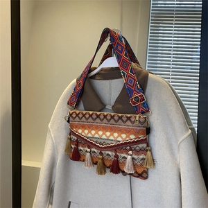 Detail of bohemian woven crossbody bag with colorful tassels and geometric strap