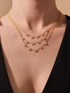 Gros plan d'un collier à trois couches plaqué or 18 carats avec pendentifs MAMA et zircons