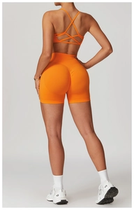 Rear view of seamless bright orange high-waist yoga shorts and cross-strap sports bra