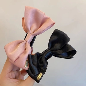 Close-up of pink and black satin bow hair clips with LOVEDAYS metal tags