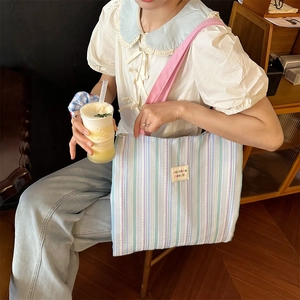 Dettaglio della borsa tote a righe in tela con tracolla rosa ed etichetta ricamata