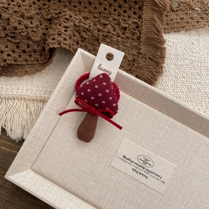 Detail of a handmade red mushroom hair clip with beige polka dots and a small bow