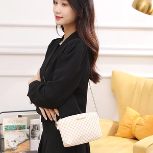 Chic women's crossbody bag with yellow dot pattern shown on a shoulder in a cozy home setting