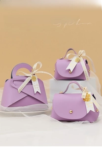Detail of hibiscus purple leather wedding favor boxes with silk ribbons and gold charms