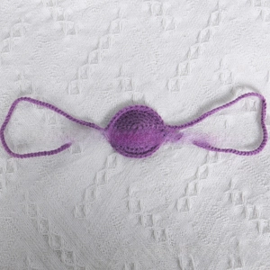 Close-up detail of purple crochet knit nose mask with intricate handmade yarn texture