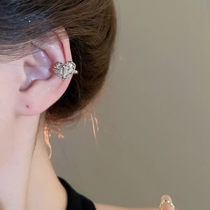 Detail shot of a silver heart ear cuff with zircons worn by a model in a close-up
