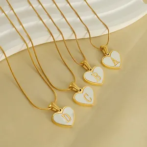 18K gold heart-shaped initial necklace with shell inlay on a white textured tray