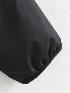 Close-up of black bomber jacket cuff with synthetic fabric texture and stitching details