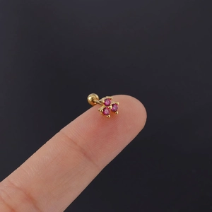 Close-up of gold clover stud earring with pink zircon stones on fingertip, screw ball back