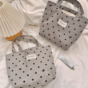 Detailed close-up of canvas tote bags featuring check pattern and bow prints
