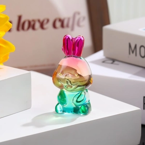 Close-up of a translucent gradient colored resin rabbit figurine on a white minimalist block