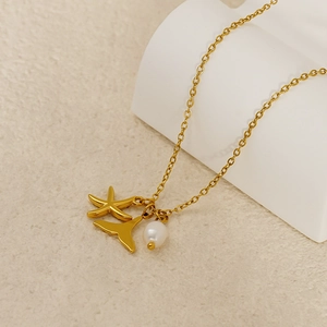 Detail shot of a gold ocean-themed necklace with starfish, whale tail and pearl charms