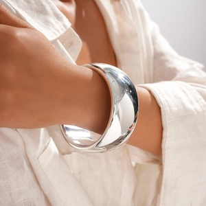 Detailed view of a wide polished silver cuff bracelet with a smooth metallic mirror finish