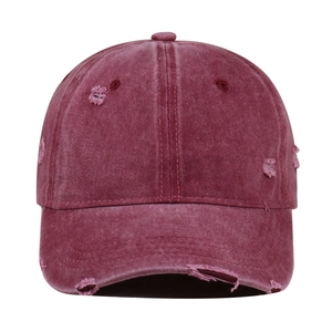 Detail shot of distressed burgundy baseball cap with washed texture and vintage frayed holes