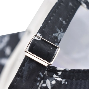 Detail of adjustable metal buckle and black fabric with white floral pattern on baseball cap