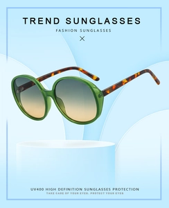 Detail of round green semi-transparent sunglasses with tortoise temples and UV400 lenses