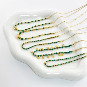Detail of 18K gold-plated stainless steel necklaces with green malachite beads on a tray