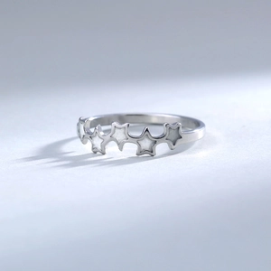 Detail of silver five-point star rings with white mother-of-pearl inlays and metal texture