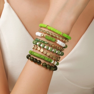 Stack of 9 green and white heishi bead bracelets with gold accents on a wrist