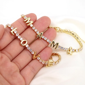 Close-up of golden MAMA and LOVE charms with cubic zirconia on a delicate chain