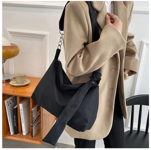 Detail of minimalist black fabric tote bag featuring knotted strap and silver hardware buckle