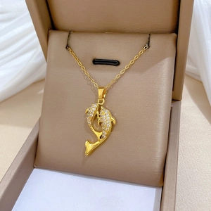 Macro shot of gold dolphin pendant with pave-set crystals on a brown velvet box