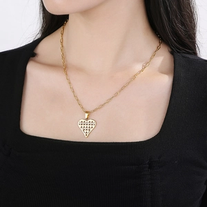 Detail of a gold heart pendant necklace with geometric cutout on a paperclip chain